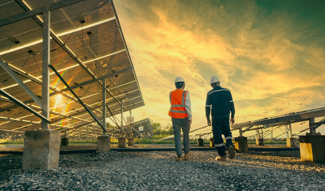 Low angle view of technician walks with investor through field of solar panels, Alternative energy to conserve the world's energy, Photovoltaic module idea for clean energy production.